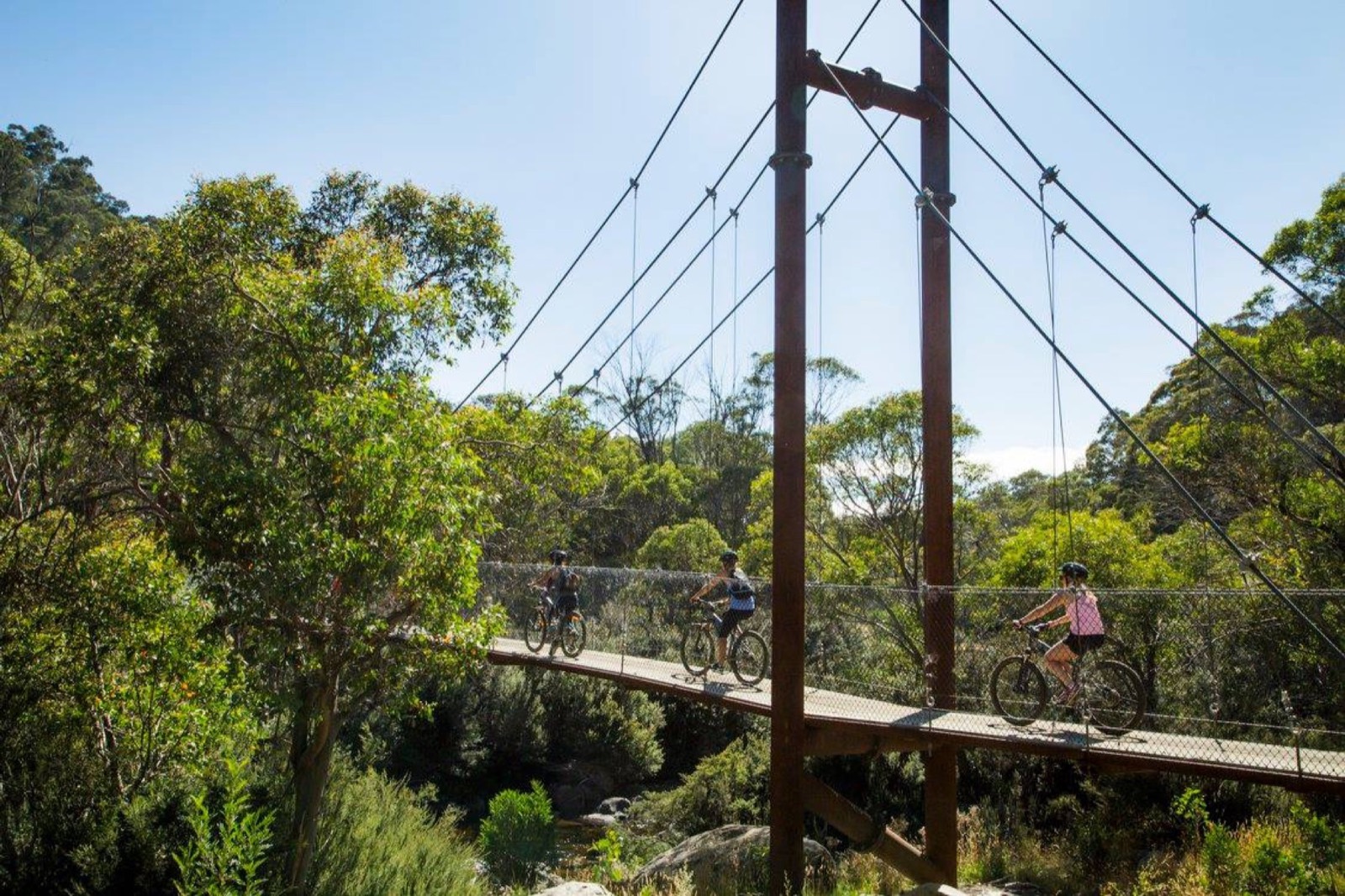 Cyclists crossing a suspension bridge in the mountains