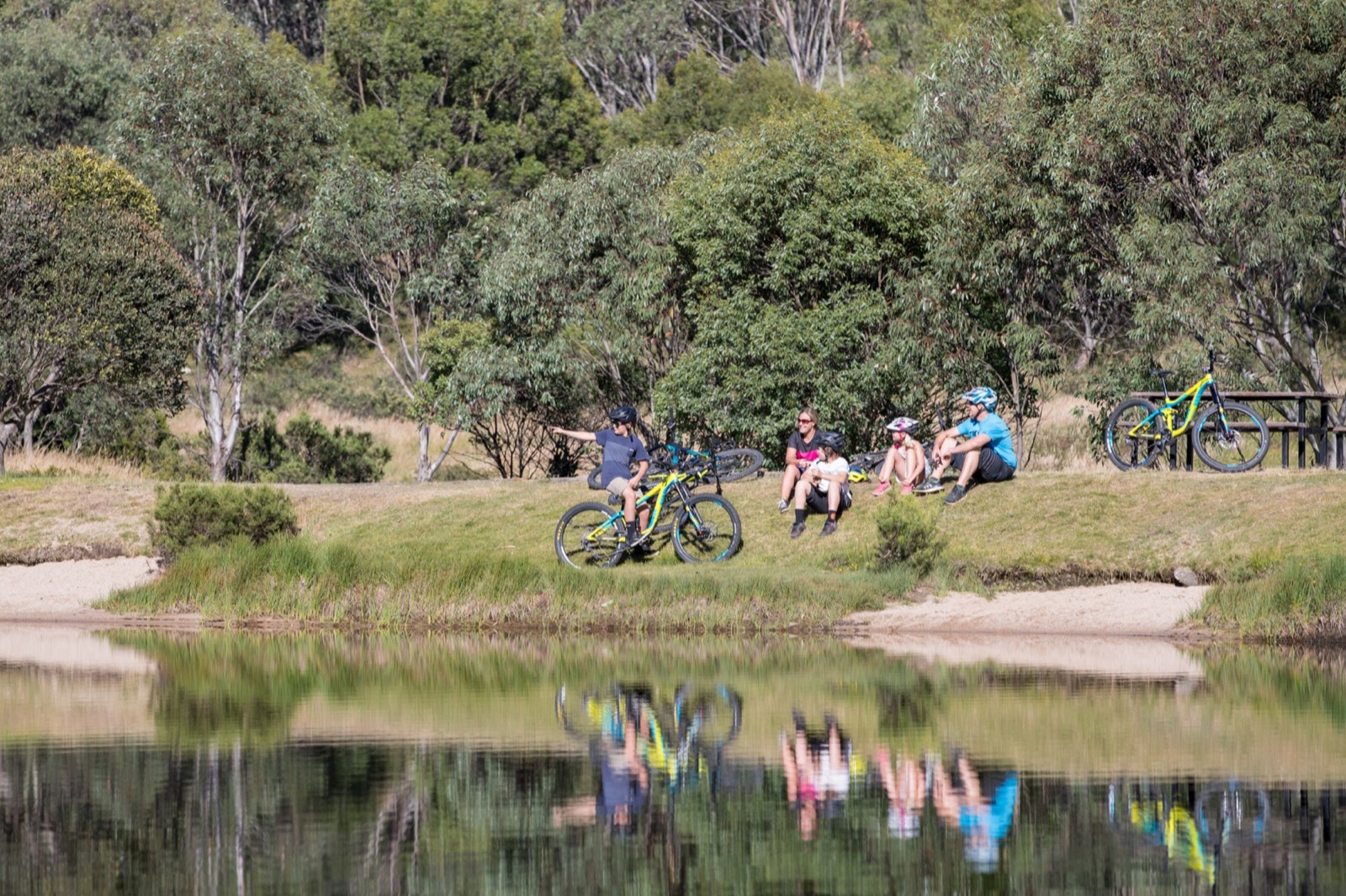A family resting with mountain bikes beside an alpine lake
